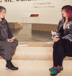 (zdjęcie przedstawia Joannę Krakowską i Sylwię Chutnik siedzące na stopniach audytorium w przestrzeni wystawy \