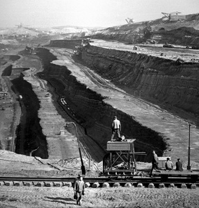 (zdjęcie czarno-białe, przedstawia kopalnię odkrywkową, tory i kilka postaci ludzkich)