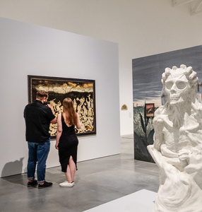 Dwie osoby przyglądają się obrazom na wystawie Aleksandry Waliszewskiej