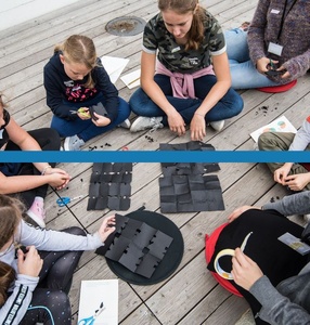 Zdjęcie. Grupa dzieci układa na podłodze kompozycje z czarnych kawałków papieru.