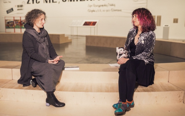 (zdjęcie przedstawia Joannę Krakowską i Sylwię Chutnik siedzące na stopniach audytorium w przestrzeni wystawy \