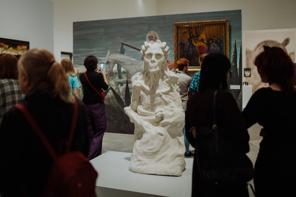 Zdjęcie. Grupa ludzi zwiedzających wystawę zgromadzona wokół jednej z rzeźb Aleksandry Waliszewskiej.
