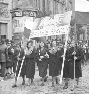Zdjęcie czarno-białe przedstawiające kobiety niosące transparent z napisem: budujcie szkoły.