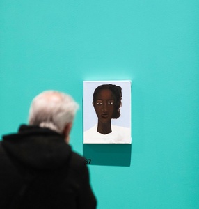 [picture of a person watching a portrait hanging on a green museum\'s wall]