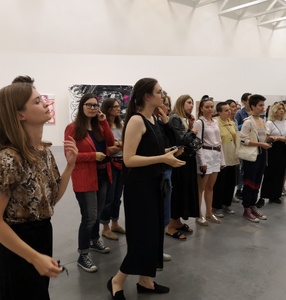 Grupa osób słucha wykładu w przestrzeni wystawowej Muzeum Sztuki Nowoczesnej w Warszawie