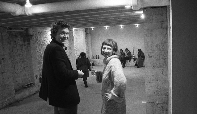 Zdjęcie czarno-białe. Anka Ptaszkowska i Bernd Lohaus stoją odwróceni twarzą do obiektywu. Uśmiechają się. Zdjęcie zrobione jest w podziemiach. Widać surowe mury i niskie sufity. Brak okien. W tle kilka osób siedzi na betonowych oparciach.