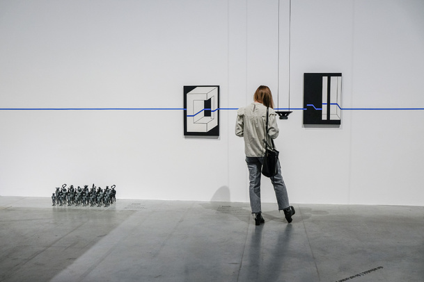 Zdjęcie. Kolorowa. Kobieta obrócona tyłem do obiektywu ogląda prace na wystawie Anna Ptaszkowska. Przypadkiem